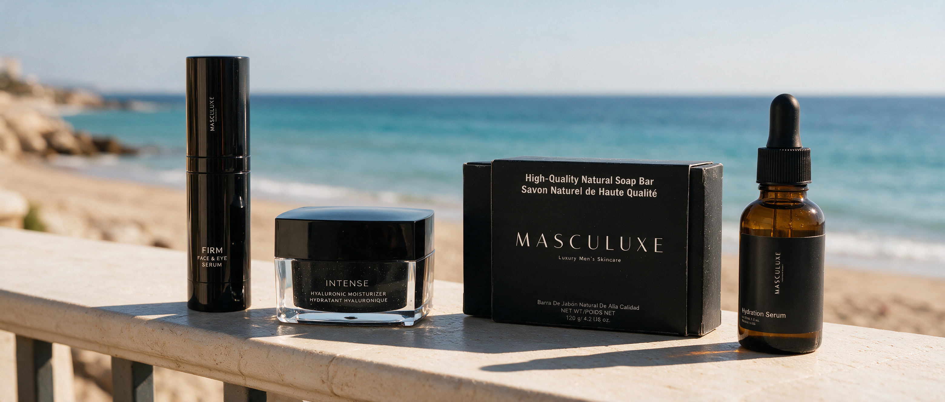 Four skincare products from the brand MASCULUXE are arranged on a wooden railing with a beach and ocean background. The products include a tall black bottle, a black jar, a black box, and an amber dropper bottle.